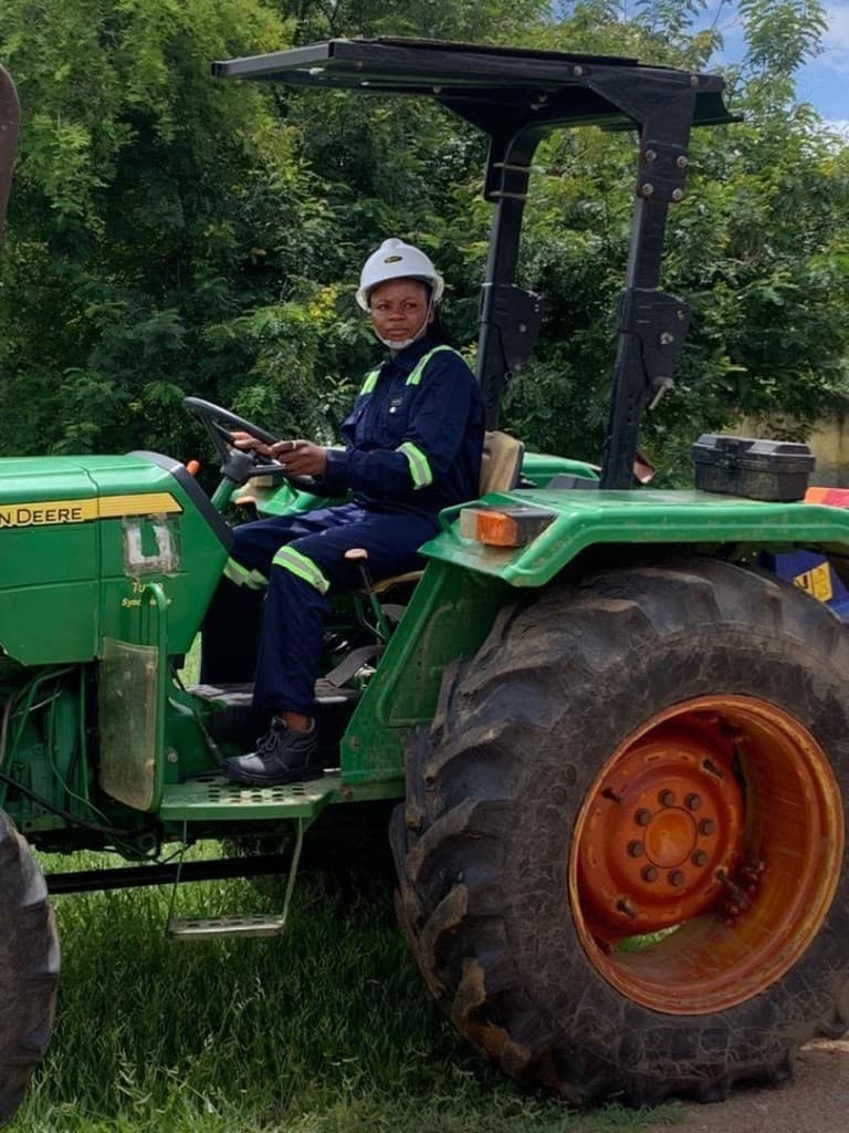 Professional farm operator driving a John Deere tractor in Ghana