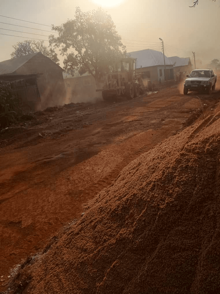 Active road construction site with grading equipment and project vehicles in Ghana